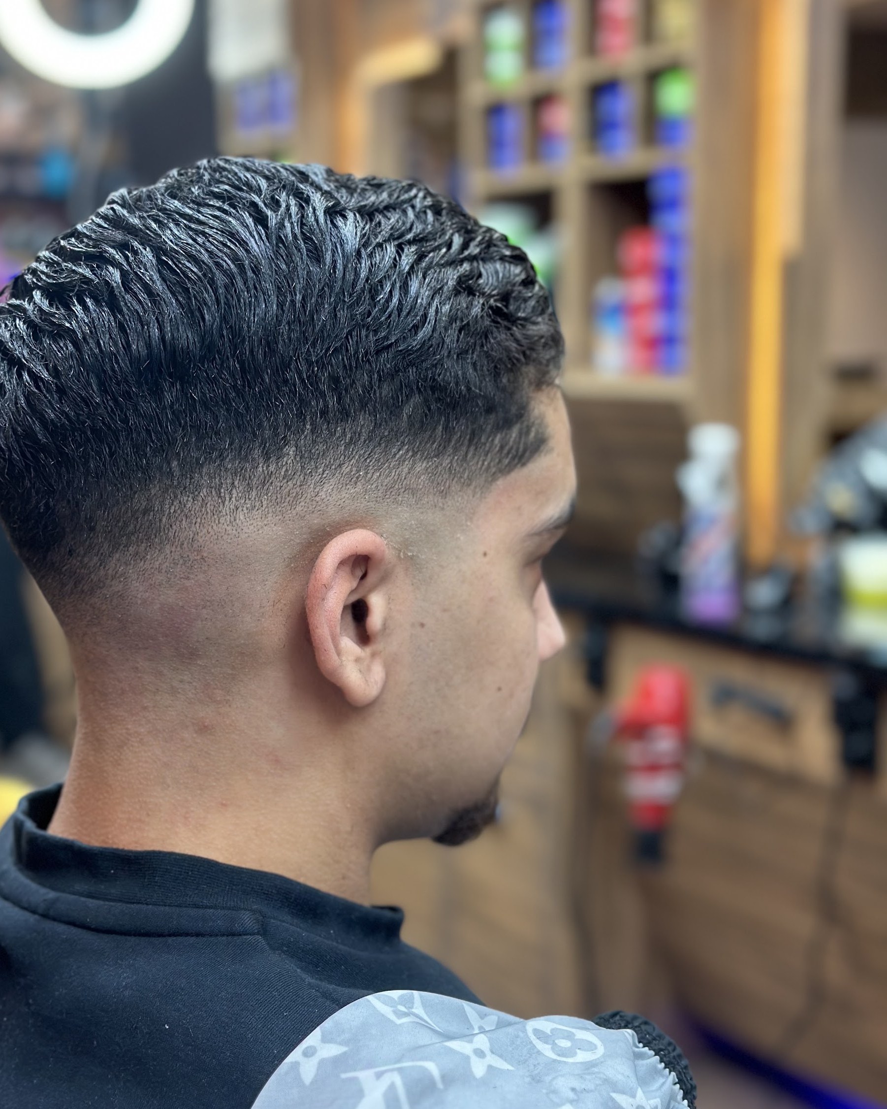 Skin fade met lengte en slag bovenop, van opzij gezien in de zaak