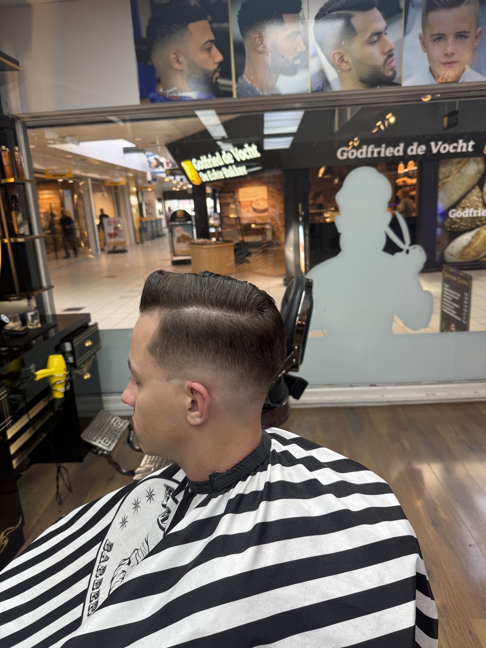 Zijscheiding met een korte fade aan de zijkant, klant in een gestreepte kapmantel