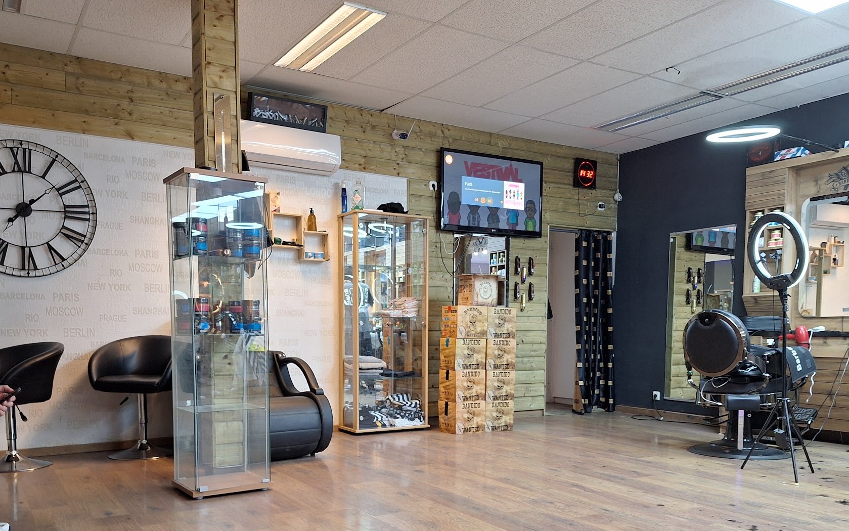 De zaak van binnen: houten wand met de grote wandklok, vitrinekasten, wachtstoelen en de barbierstoel achterin