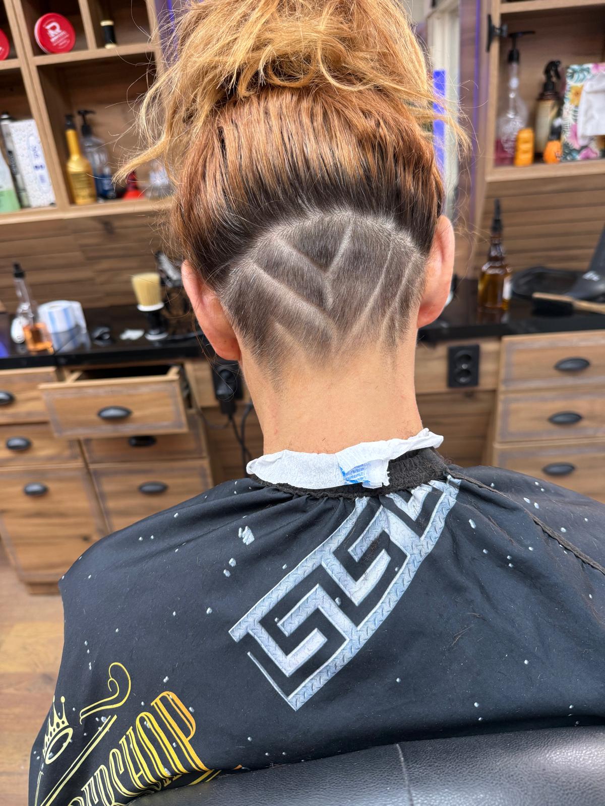 Undercut met een geschoren patroon in de nek van een vrouw met opgestoken haar
